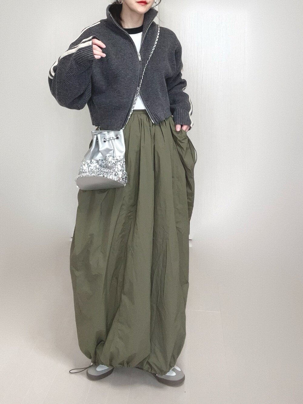 グレー系のニット/セーター、シルバー系のショルダーバッグ、グリーン系のスカートを着用したレディースの冬コーディネートの5枚目の写真
