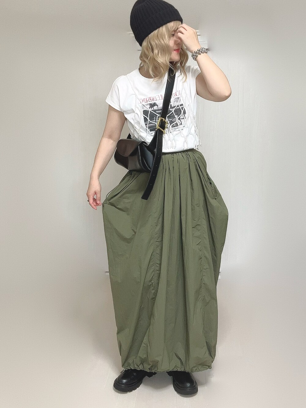 ブラック系のブーツ、グリーン系のスカート、ホワイト系のベストを着用したレディースの秋コーディネートの2枚目の写真