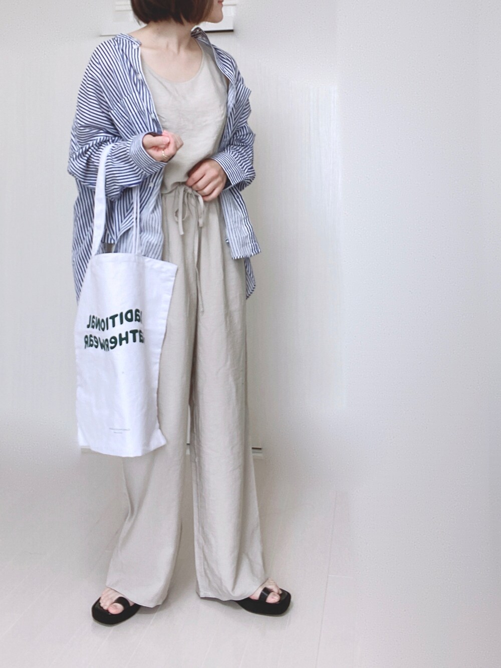 ブルー系のシャツ/ブラウス、ホワイト系のトートバッグ、ブラック系のサンダルを着用したレディースの夏コーディネートの3枚目の写真