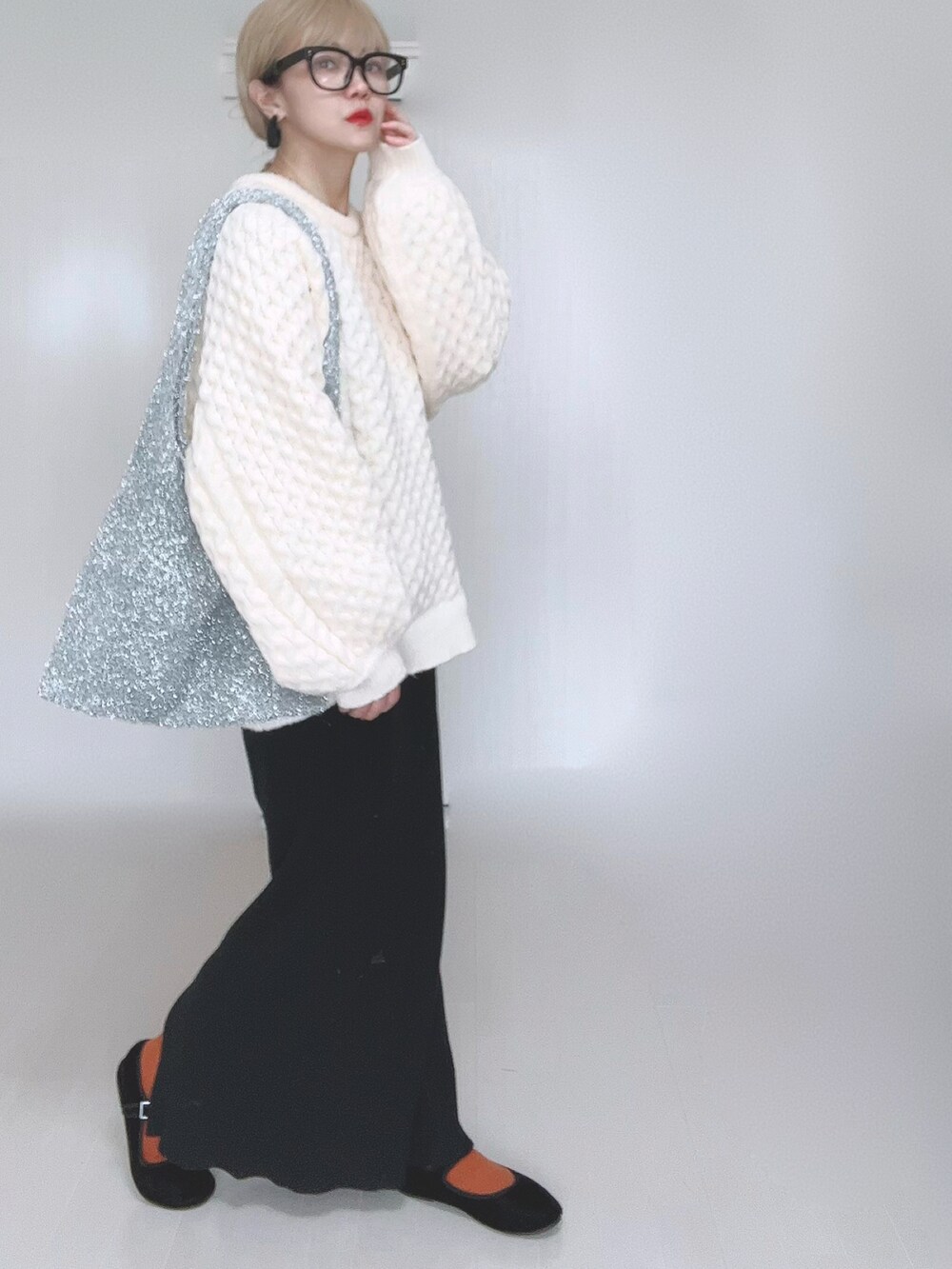 ホワイト系のニット/セーター、ブラック系のスカート、ブラック系のパンプスを着用したレディースの冬コーディネートの2枚目の写真