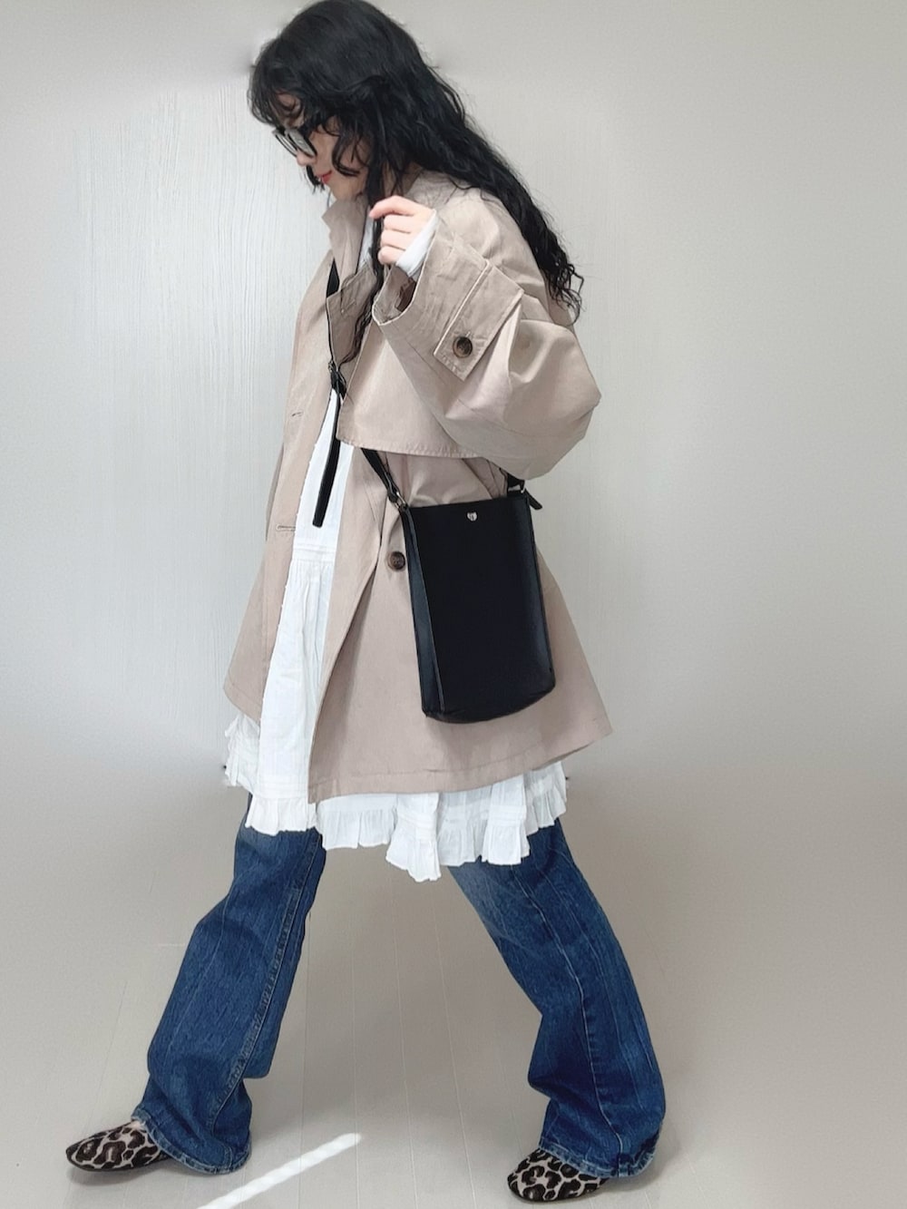 ベージュ系のトレンチコート、ホワイト系のワンピース、ブラック系のショルダーバッグを着用したレディースの春コーディネートの4枚目の写真