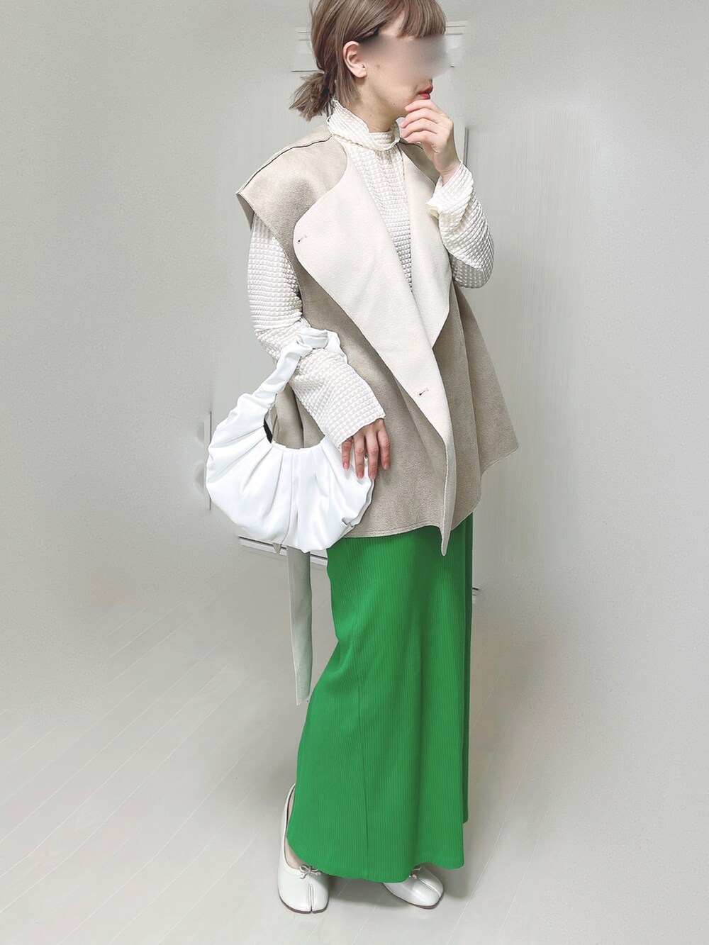 ホワイト系のTシャツ/カットソー、ベージュ系のベスト、グリーン系のスカートを着用したレディースの春コーディネートの2枚目の写真