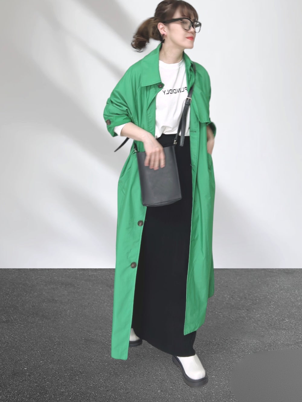 グリーン系のトレンチコート、ブラック系のショルダーバッグ、ブラック系のスカートを着用したレディースの秋コーディネートの4枚目の写真