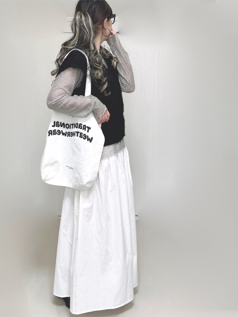 ブラック系のベスト、ホワイト系のシャツ/ブラウス、ホワイト系のトートバッグを着用したレディースの秋コーディネートの2枚目の写真