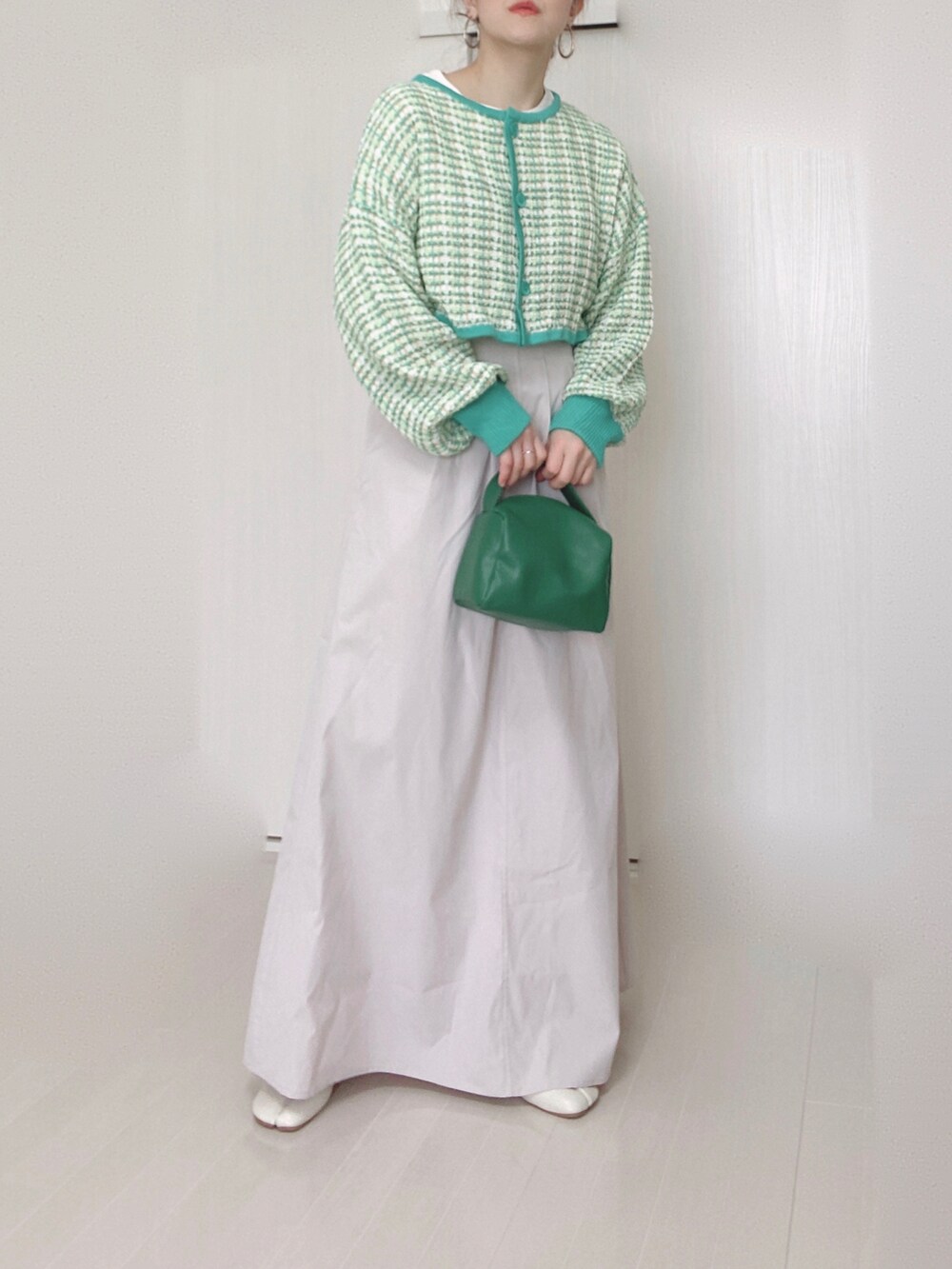 グリーン系のカーディガン/ボレロ、ベージュ系のスカート、グリーン系のハンドバッグを着用したレディースの春コーディネートの3枚目の写真