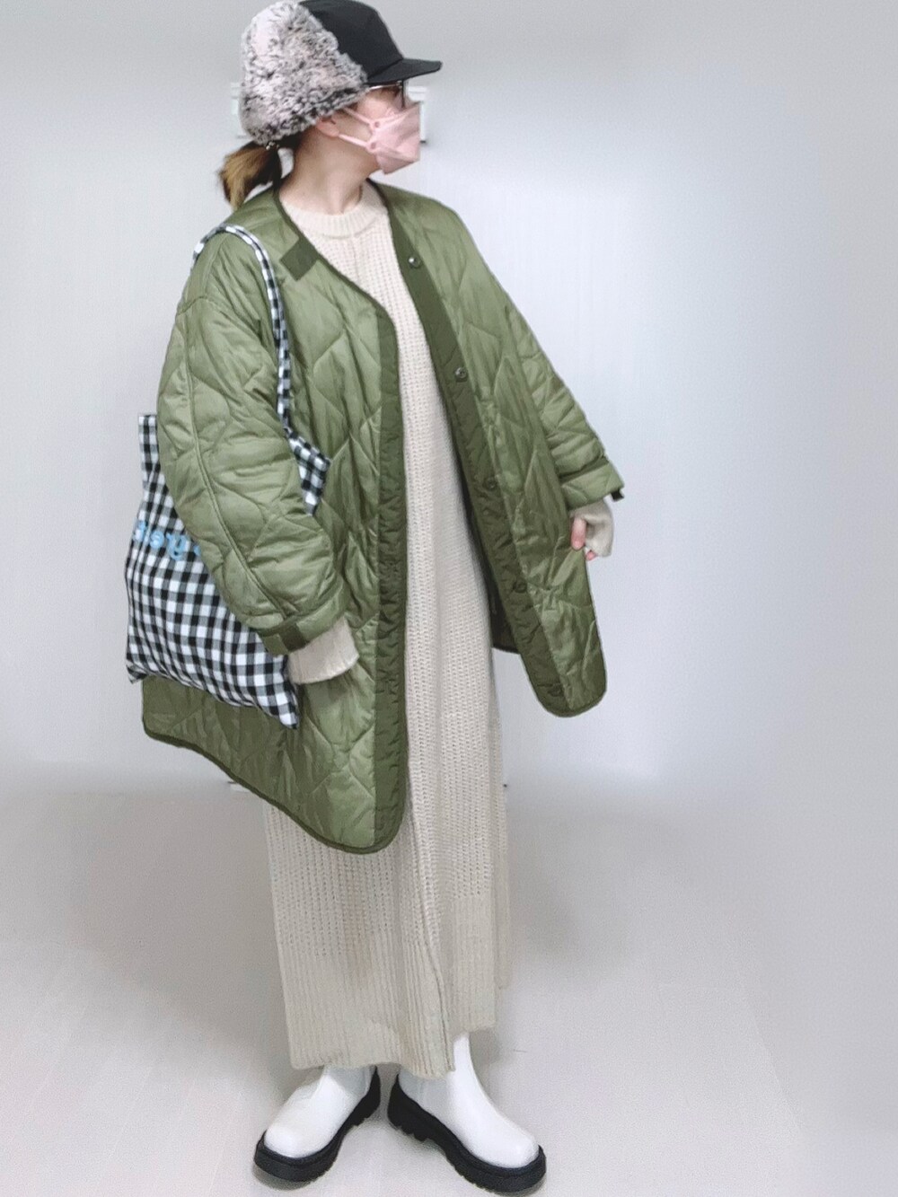 ホワイト系のワンピース、グリーン系のミリタリージャケット、ホワイト系のブーツを着用したレディースの冬コーディネートの2枚目の写真