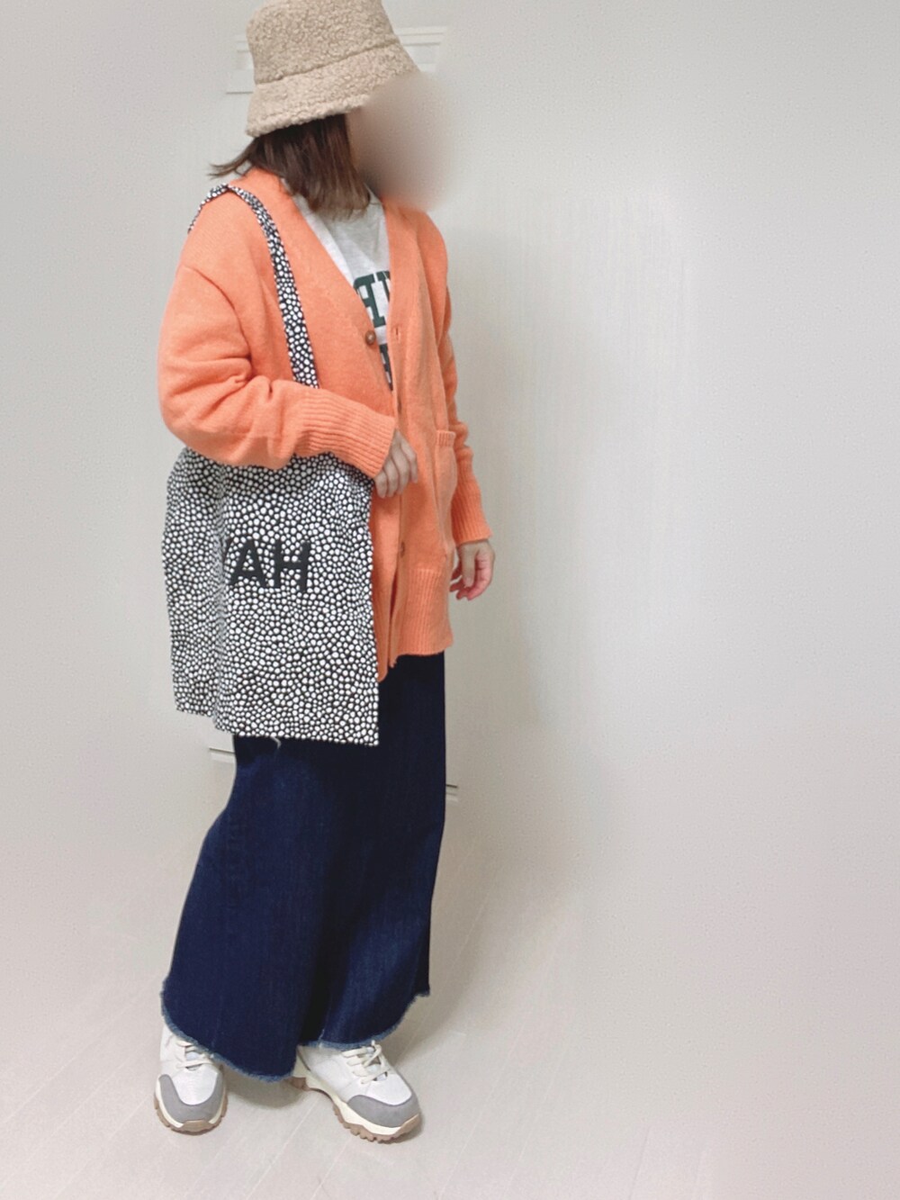 オレンジ系のカーディガン/ボレロ、ブルー系のデニムスカート、ベージュ系のスニーカーを着用したレディースの秋コーディネートの3枚目の写真