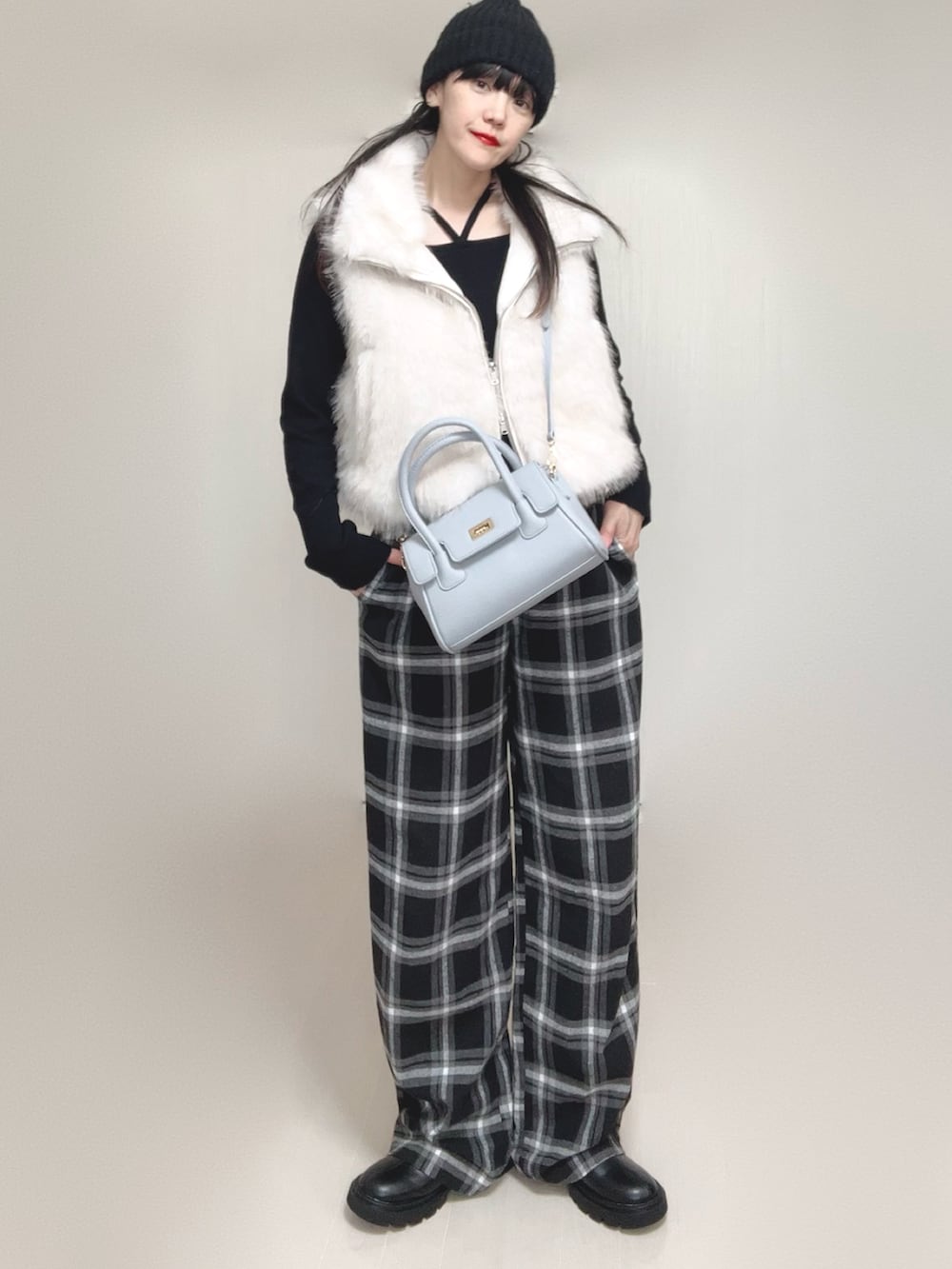 ホワイト系のベスト、ブラック系のTシャツ/カットソー、ブラック系のブーツを着用したレディースの秋コーディネートの2枚目の写真