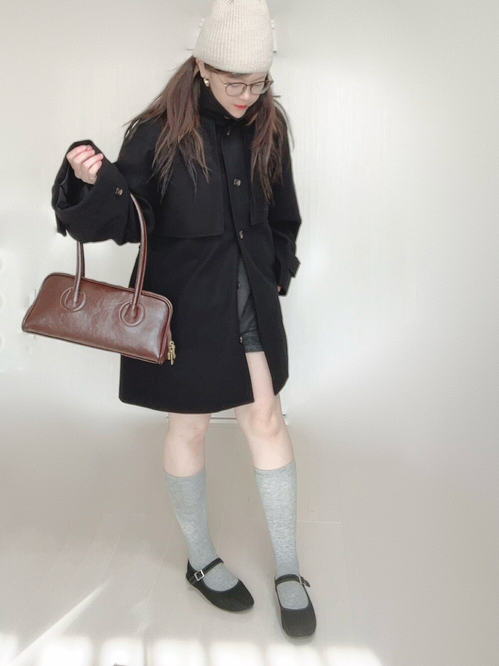 グレー系のトレンチコート、ブラウン系のショルダーバッグ、ブラック系のパンプスを着用したレディースの秋コーディネートの2枚目の写真