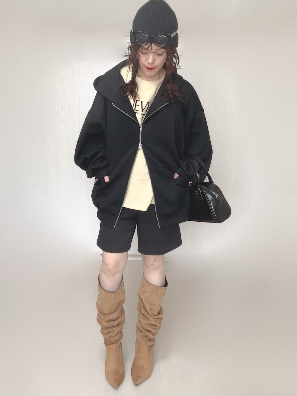 ブラック系のパーカー、ブラック系のボストンバッグ、ベージュ系のTシャツ/カットソーを着用したレディースの冬コーディネートの2枚目の写真