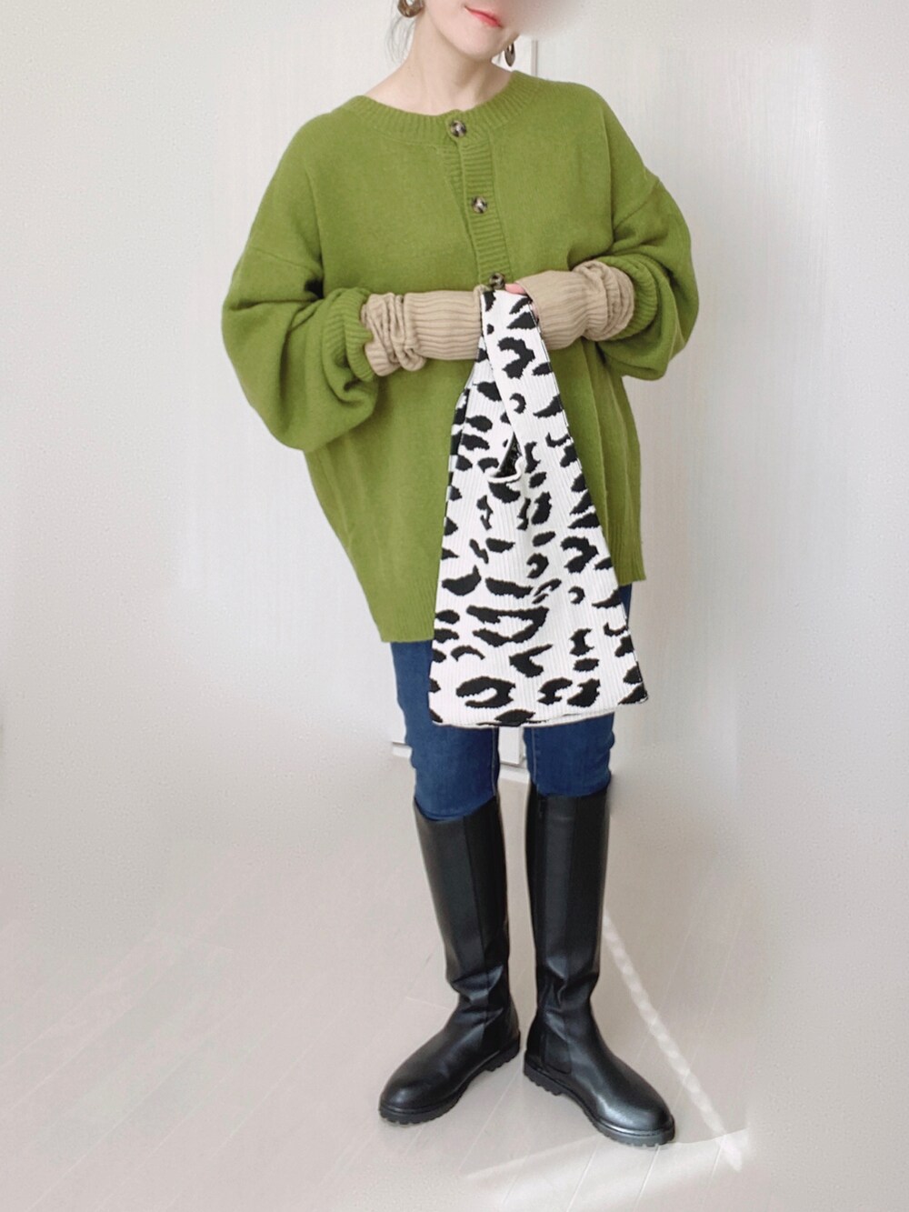 グリーン系のカーディガン/ボレロ、ブルー系のデニムパンツ、ブラック系のブーツを着用したレディースの秋コーディネートの3枚目の写真