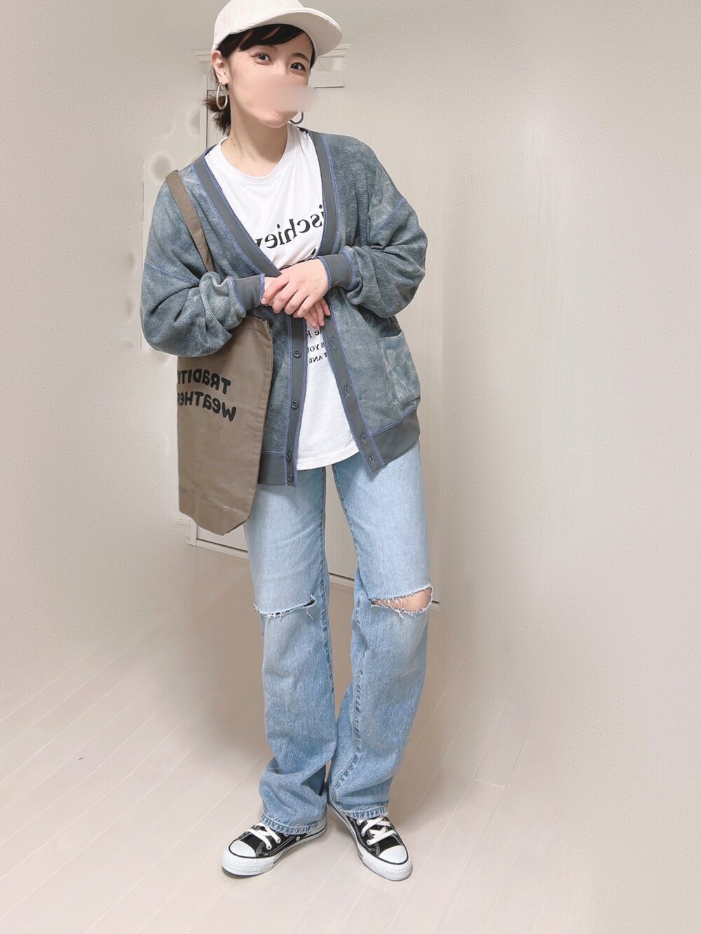 ブルー系のデニムパンツ、ブラック系のカーディガン/ボレロ、ブラウン系のトートバッグを着用したレディースの春コーディネートの4枚目の写真