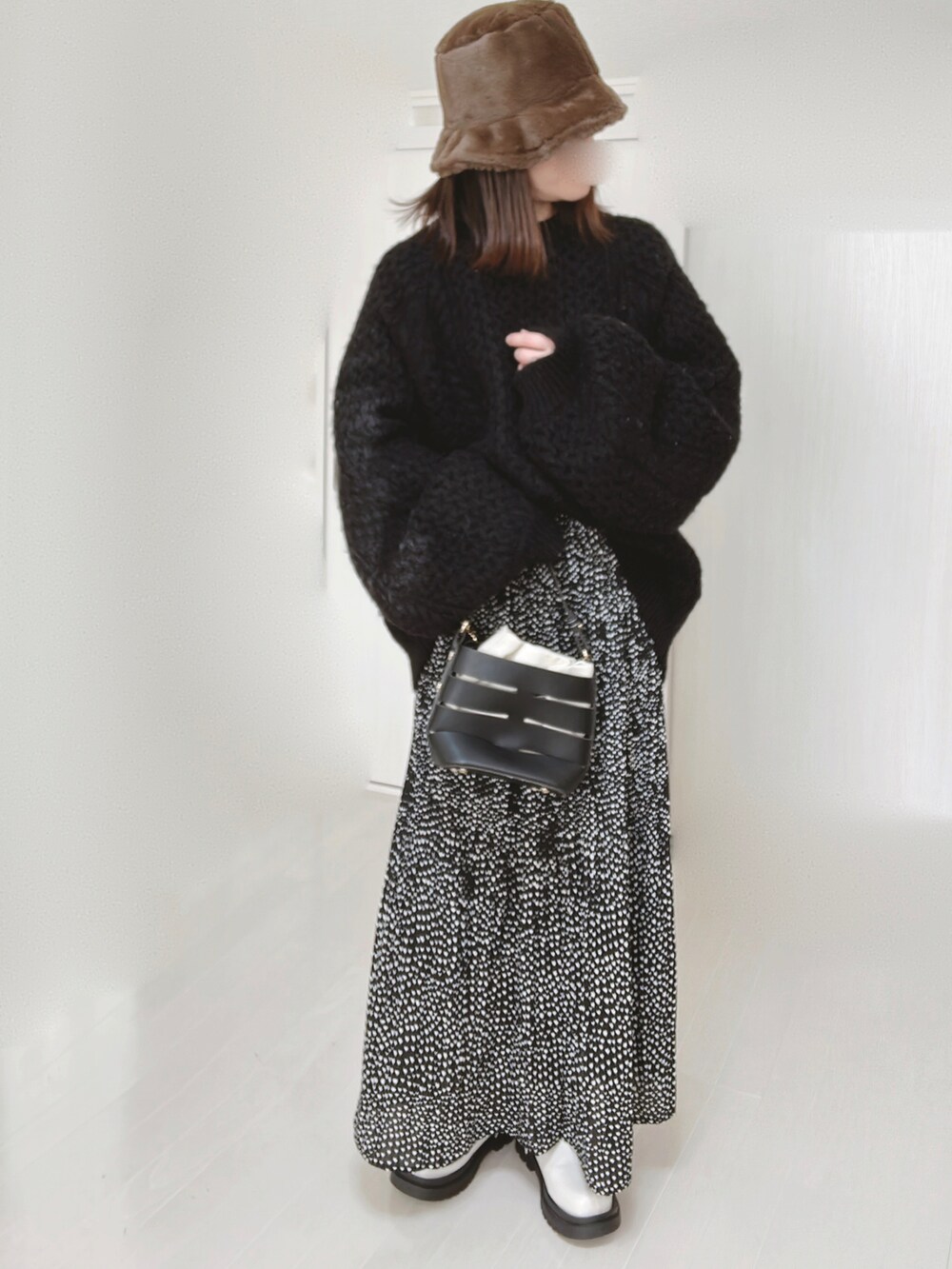 ブラック系のニット/セーター、ブラック系のショルダーバッグ、ブラック系のスカートを着用したレディースの冬コーディネートの3枚目の写真