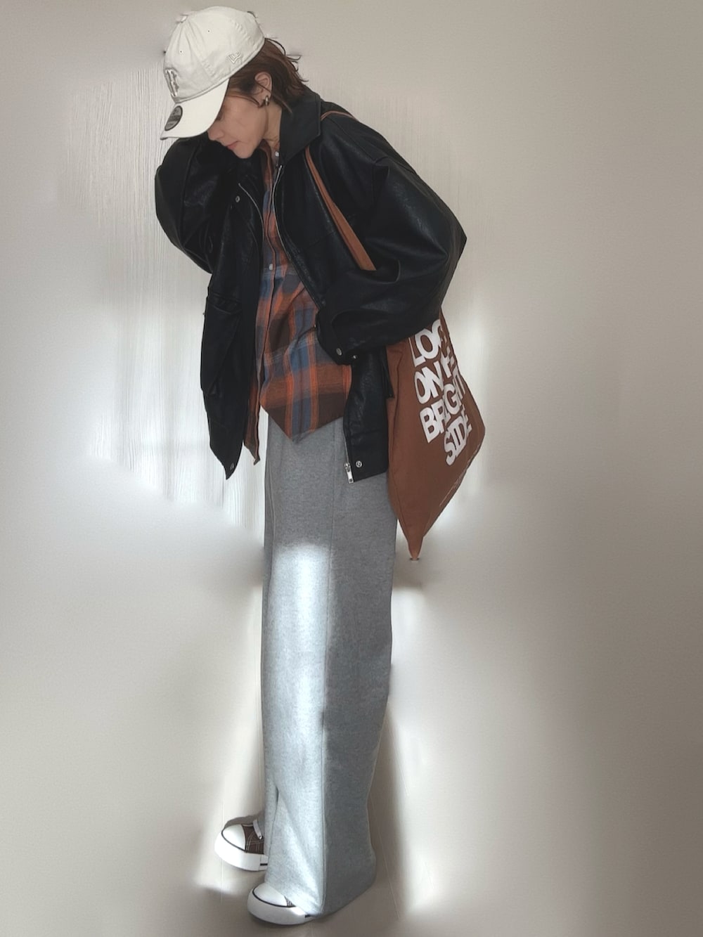 ブラック系のブルゾン、ブラウン系のトートバッグ、ベージュ系のキャップを着用したレディースの冬コーディネートの2枚目の写真