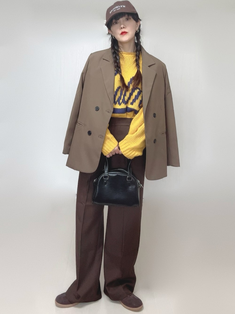 イエロー系のニット/セーター、ブラウン系のテーラードジャケット、ブラウン系のその他パンツを着用したレディースの冬コーディネートの3枚目の写真