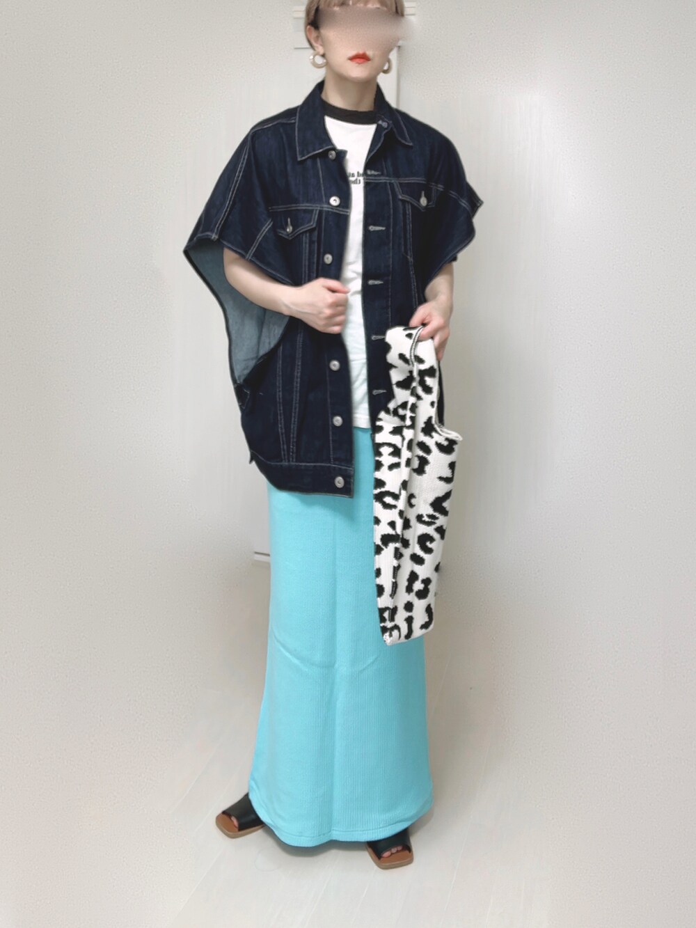 ブルー系のベスト、ブルー系のスカート、ブラック系のサンダルを着用したレディースの春コーディネートの5枚目の写真