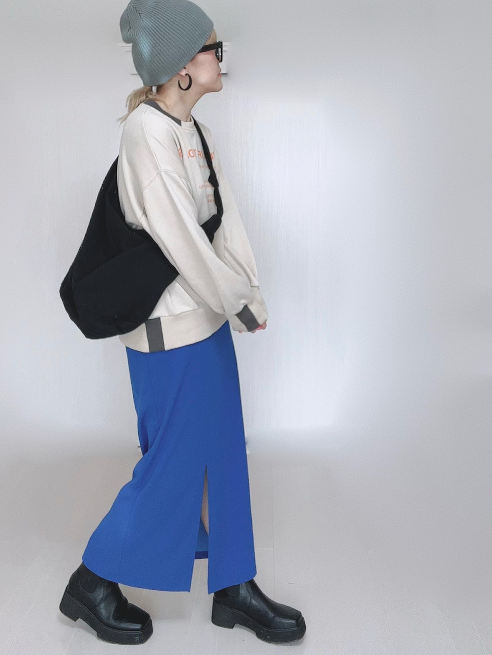 ベージュ系のスウェット、ブルー系のスカート、ブラック系のブーツを着用したレディースの冬コーディネートの3枚目の写真