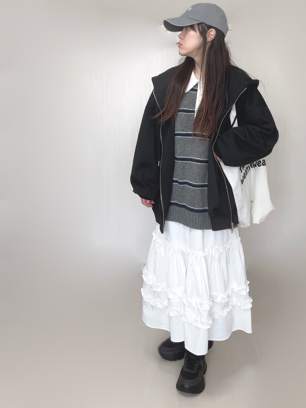 ブラック系のパーカー、グレー系のニット/セーター、ホワイト系のスカートを着用したレディースの春コーディネートの3枚目の写真