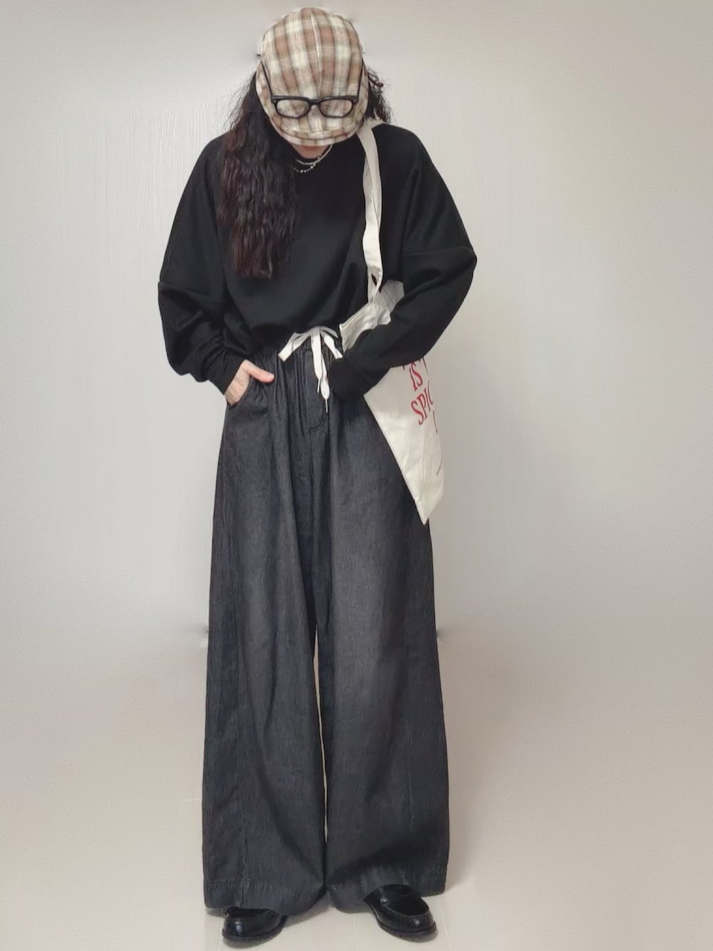 ブラック系のスウェット、ブラック系のデニムパンツ、ホワイト系のトートバッグを着用したレディースの春コーディネートの3枚目の写真