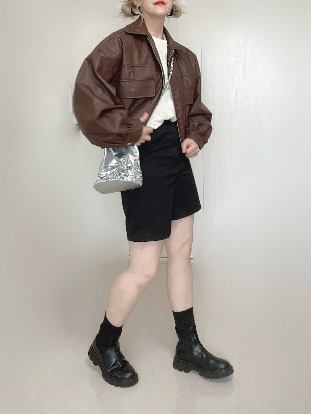 ブラウン系のブルゾン、ホワイト系のニット/セーター、ブラック系のブーツを着用したレディースの秋コーディネートの4枚目の写真