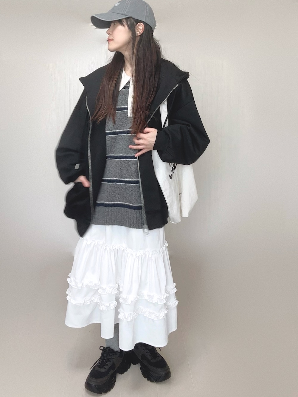 ブラック系のパーカー、グレー系のニット/セーター、ホワイト系のスカートを着用したレディースの春コーディネートの4枚目の写真
