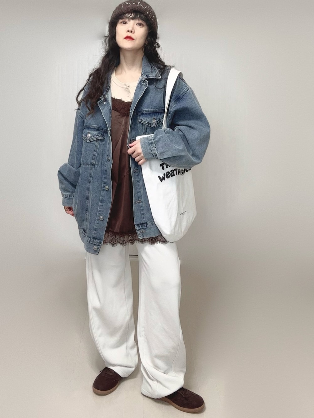 ホワイト系のニット/セーター、ブルー系のデニムジャケット、ホワイト系のトートバッグを着用したレディースの春コーディネートの3枚目の写真