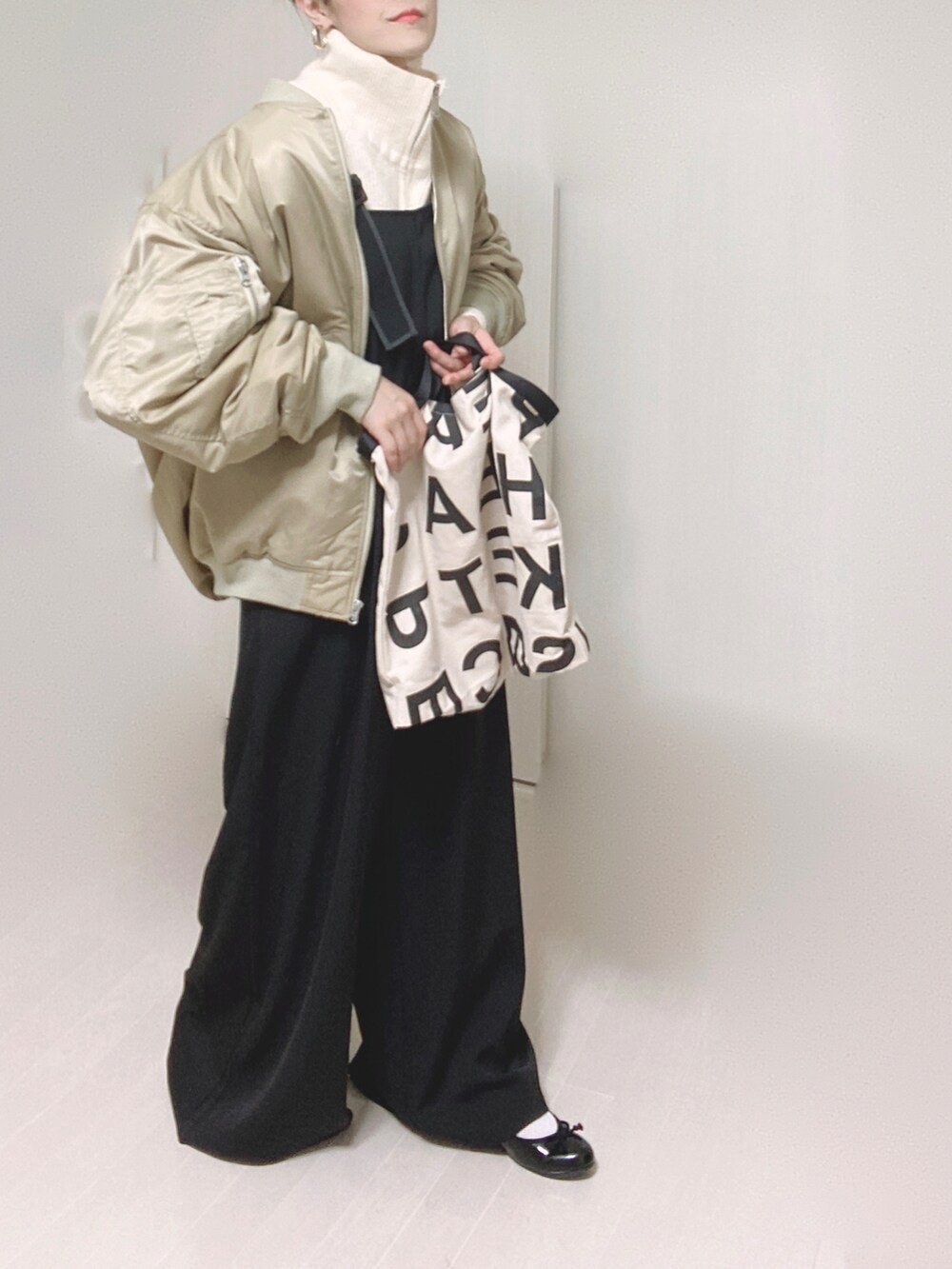 ベージュ系のMA-1、ブラック系のサロペット/オーバーオール、ホワイト系のニット/セーターを着用したレディースの冬コーディネートの3枚目の写真