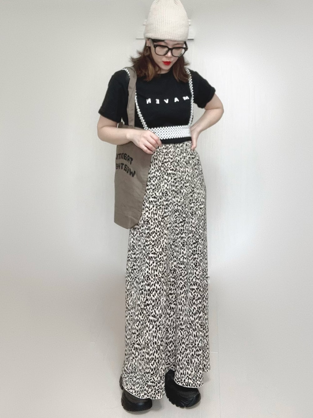 ベージュ系のスカート、ブラック系のTシャツ/カットソー、ブラック系のスニーカーを着用したレディースの春コーディネートの2枚目の写真