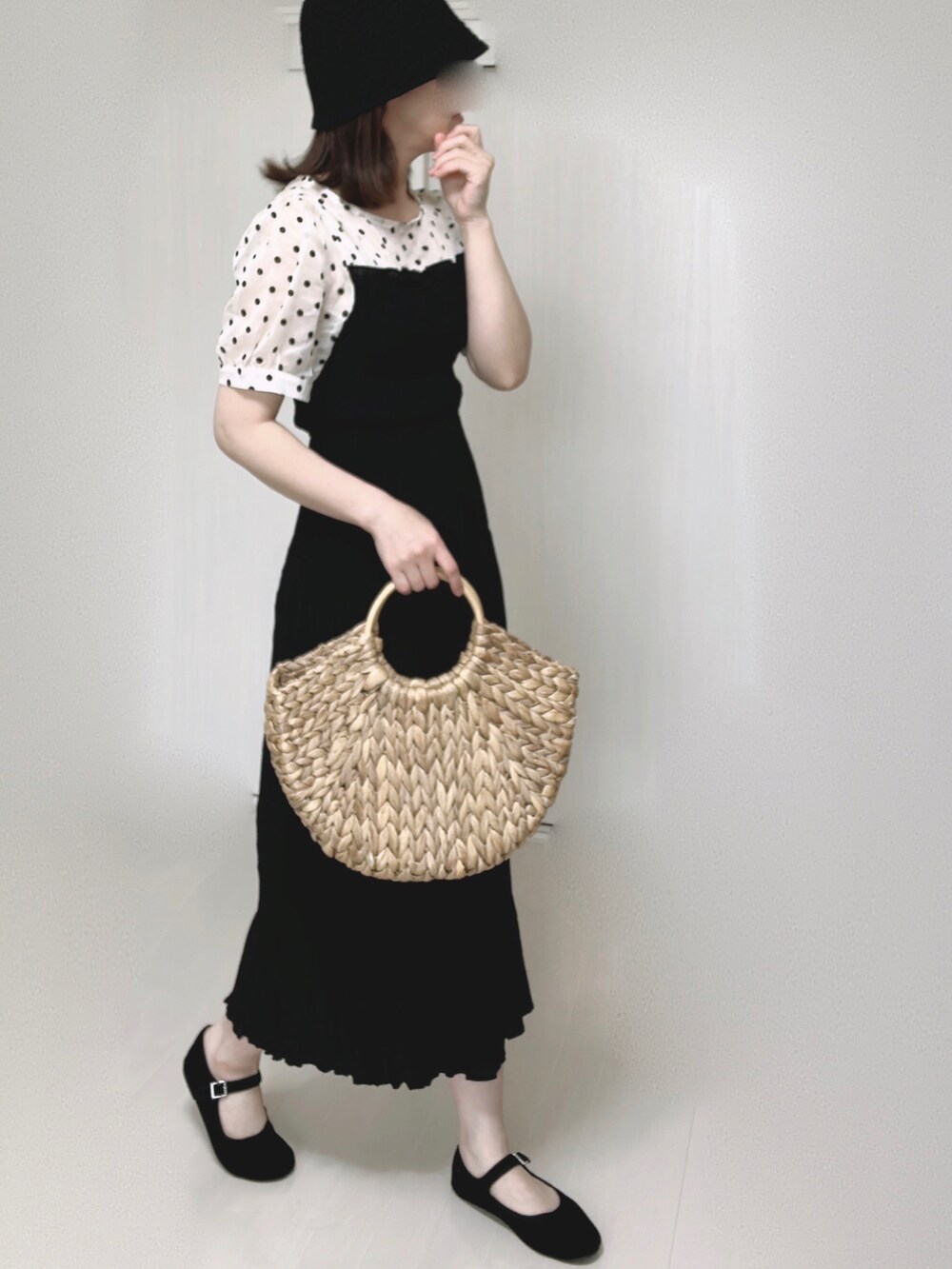 ベージュ系のかごバッグ、ブラック系のワンピース、ブラック系のパンプスを着用したレディースの夏コーディネートの2枚目の写真