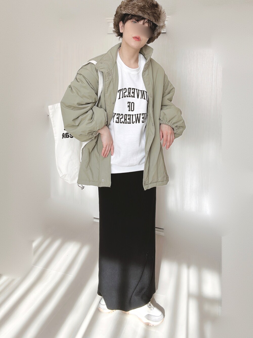 ホワイト系のスウェット、グリーン系のダウンジャケット/コート、ブラック系のスカートを着用したレディースの冬コーディネートの2枚目の写真