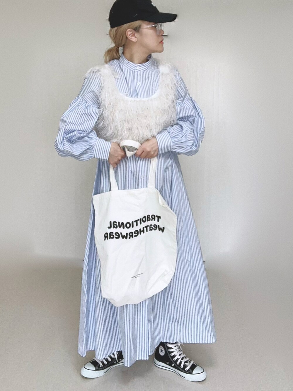 ブルー系のシャツワンピース、ホワイト系のベスト、ホワイト系のトートバッグを着用したレディースの冬コーディネートの2枚目の写真