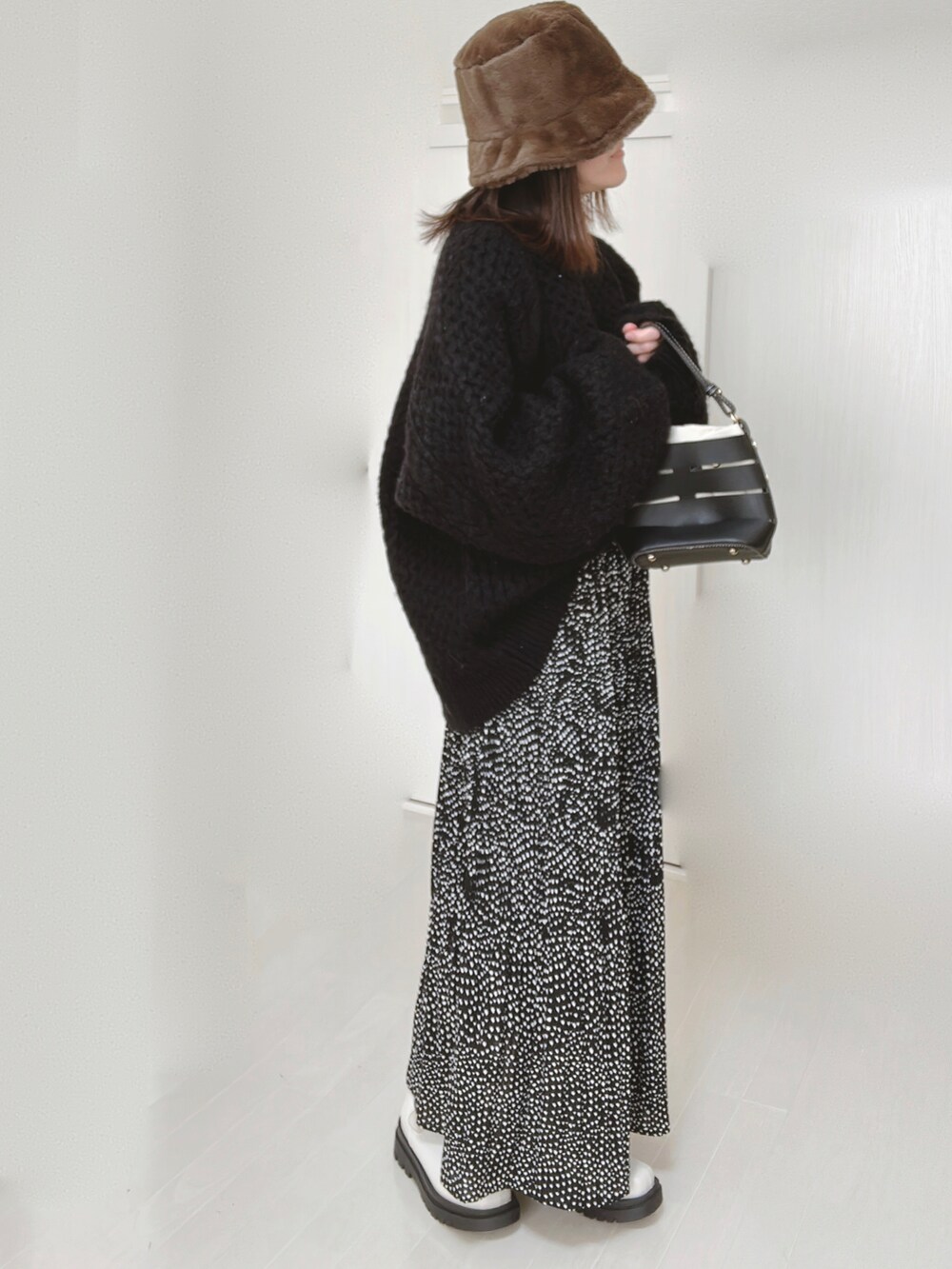 ブラック系のニット/セーター、ブラック系のショルダーバッグ、ブラック系のスカートを着用したレディースの冬コーディネートの2枚目の写真