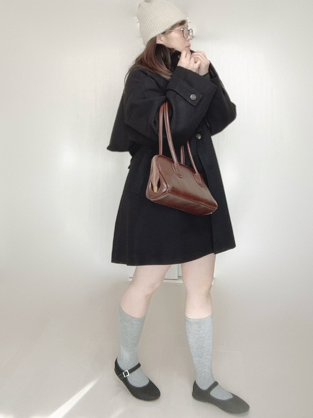 グレー系のトレンチコート、ブラウン系のショルダーバッグ、ブラック系のパンプスを着用したレディースの秋コーディネートの3枚目の写真