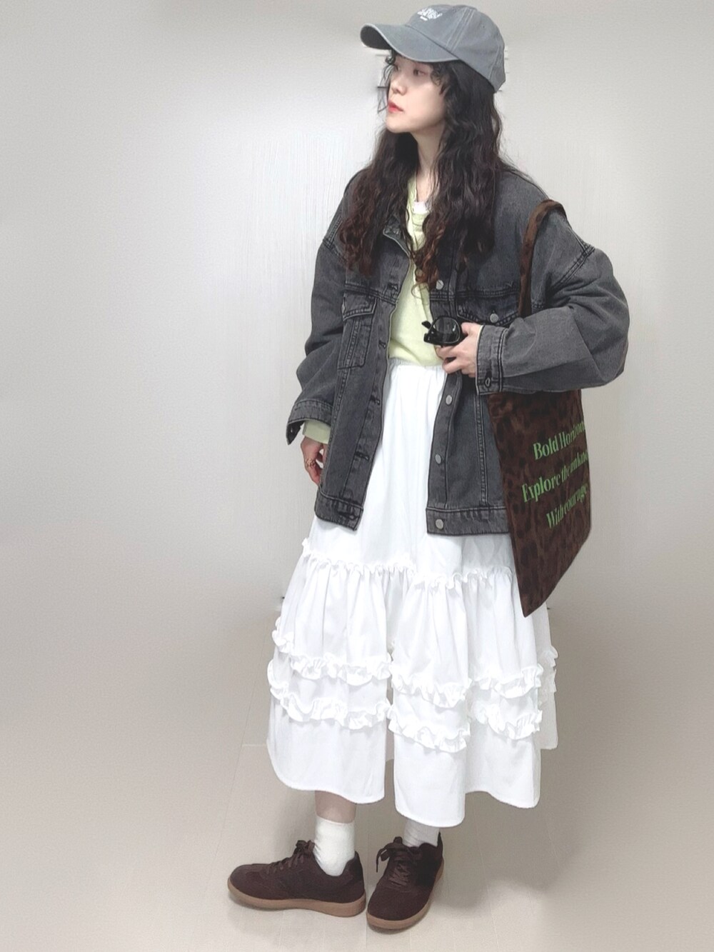 ブラック系のデニムジャケット、ホワイト系のスカート、イエロー系のTシャツ/カットソーを着用したレディースの春コーディネートの4枚目の写真