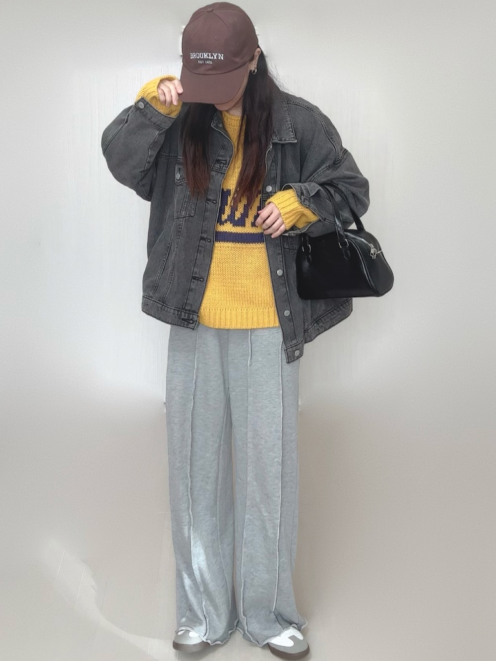 イエロー系のニット/セーター、ブラック系のデニムジャケット、グレー系のスウェットパンツを着用したレディースの冬コーディネートの2枚目の写真