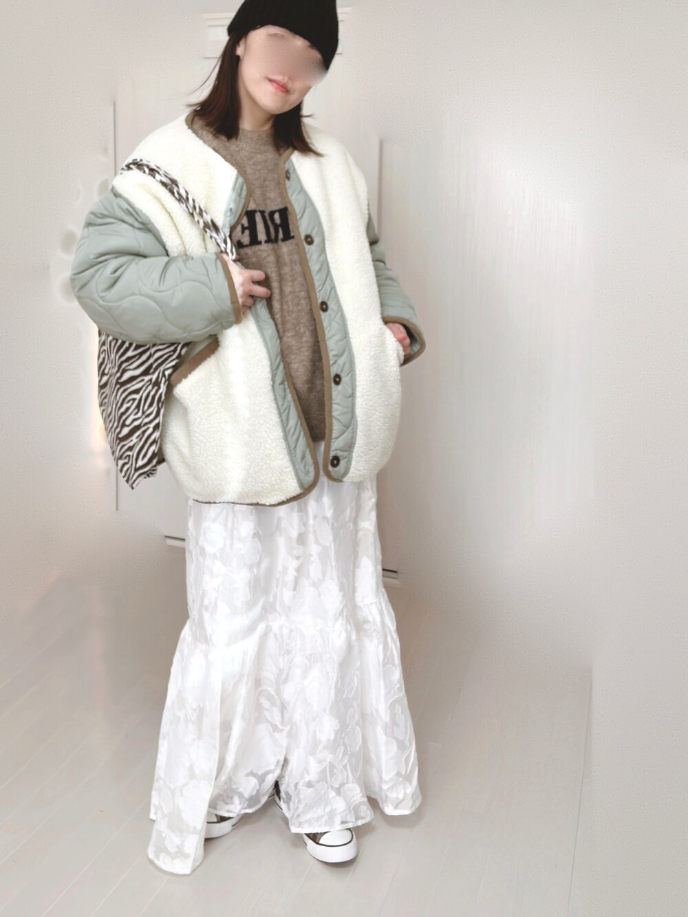 ホワイト系のノーカラージャケット、ベージュ系のニット/セーター、ホワイト系のスカートを着用したレディースの冬コーディネートの5枚目の写真