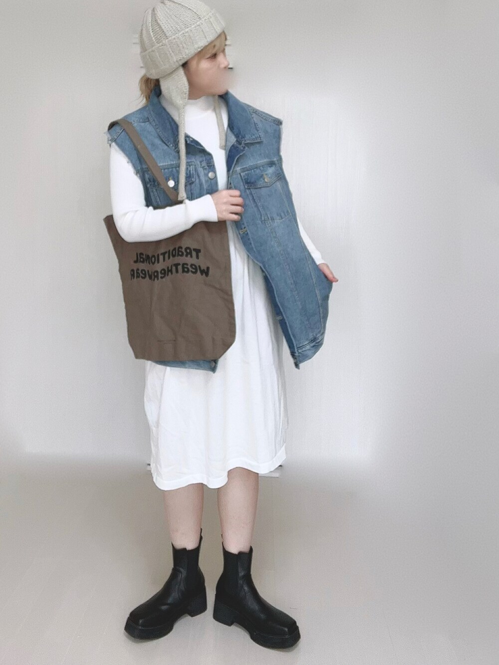 ホワイト系のワンピース、ブルー系のベスト、ブラウン系のトートバッグを着用したレディースの冬コーディネートの5枚目の写真