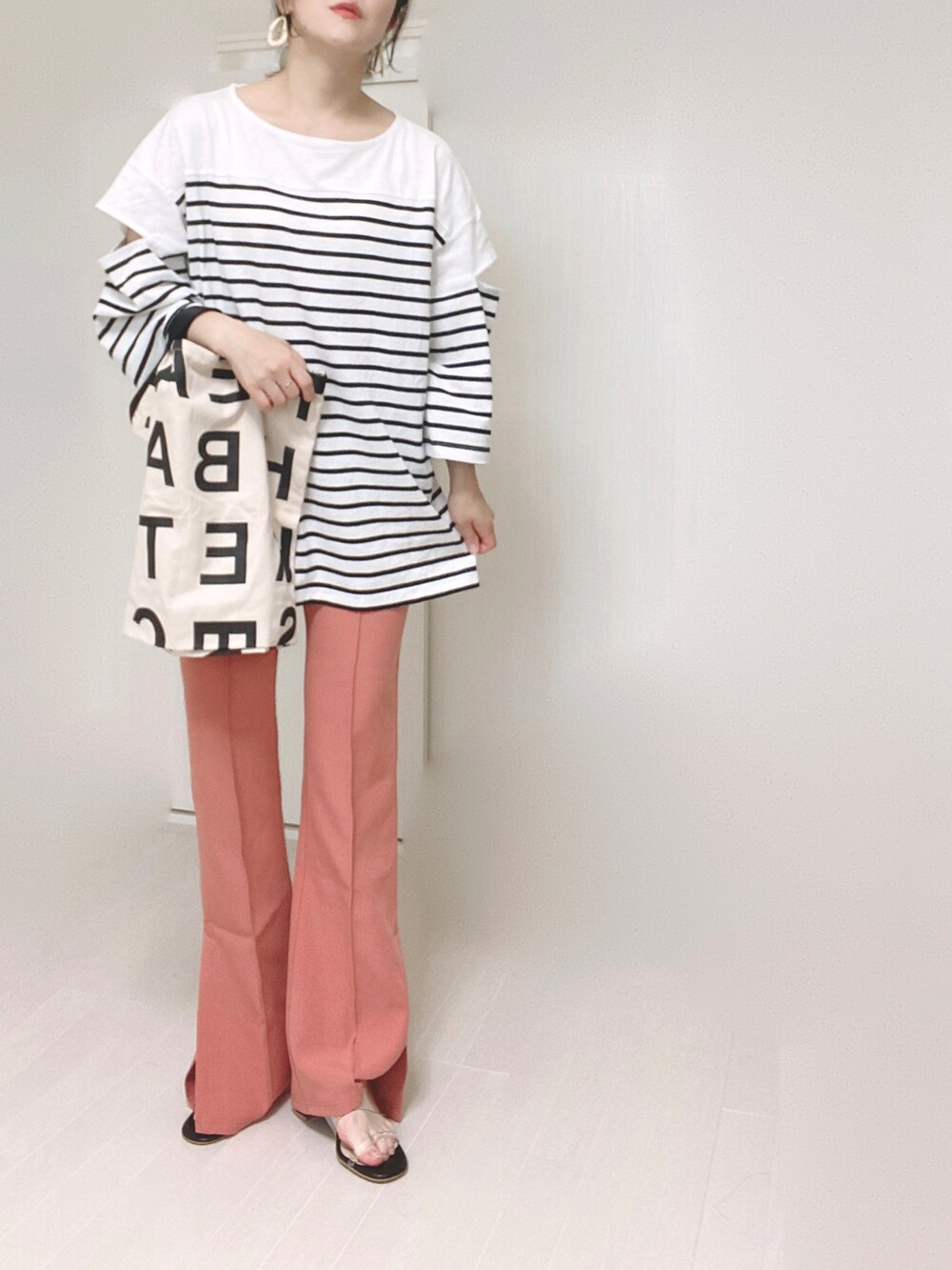 ピンク系のスラックス、ブラック系のTシャツ/カットソー、ホワイト系のトートバッグを着用したレディースの夏コーディネートの4枚目の写真