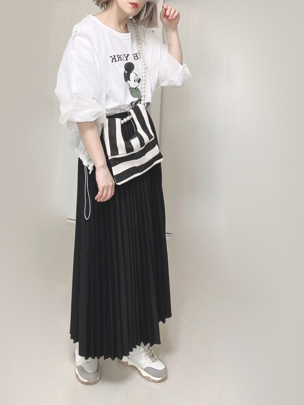 ホワイト系のTシャツ/カットソー、ホワイト系のショルダーバッグ、ブラック系のスカートを着用したレディースの春コーディネートの5枚目の写真