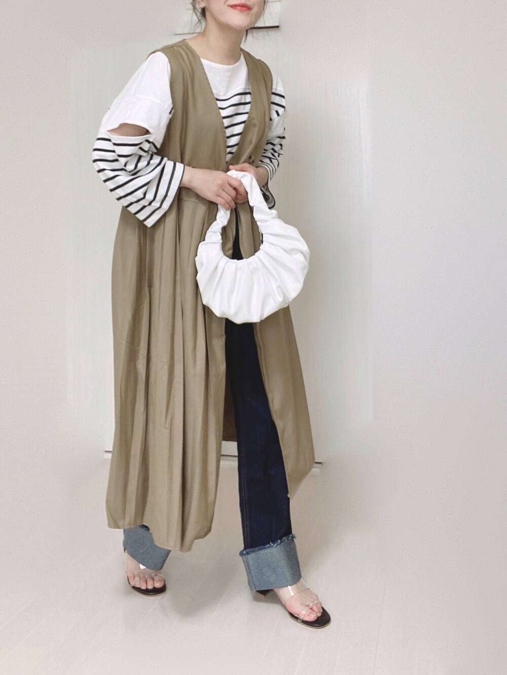 ベージュ系のワンピース、ブラック系のTシャツ/カットソー、ブルー系のデニムパンツを着用したレディースの夏コーディネートの3枚目の写真