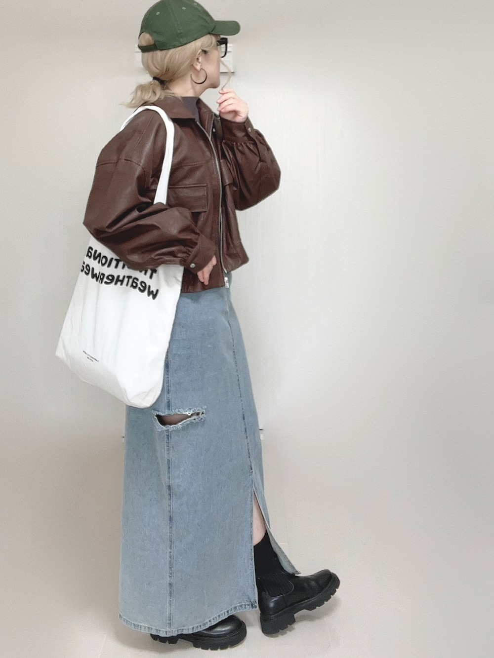 ブラウン系のブルゾン、ホワイト系のトートバッグ、ブラック系のブーツを着用したレディースの秋コーディネートの4枚目の写真