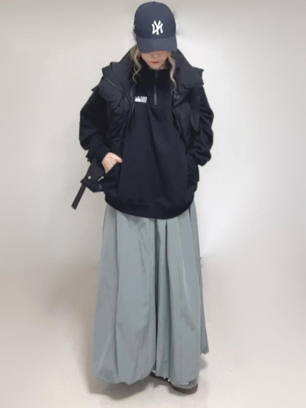 ブラック系のダウンベスト、ブラック系のスウェット、ブルー系のキャップを着用したレディースの秋コーディネートの2枚目の写真