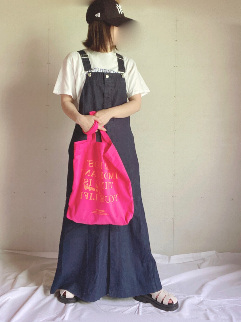 ブルー系のジャンパースカート、ホワイト系のTシャツ/カットソー、ピンク系のトートバッグを着用したレディースの夏コーディネートの3枚目の写真