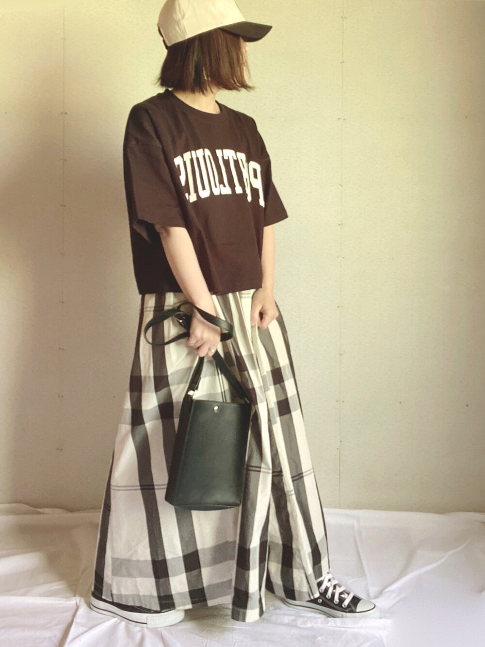 ホワイト系のスカート、ブラック系のTシャツ/カットソー、グリーン系のハンドバッグを着用したレディースの夏コーディネートの5枚目の写真