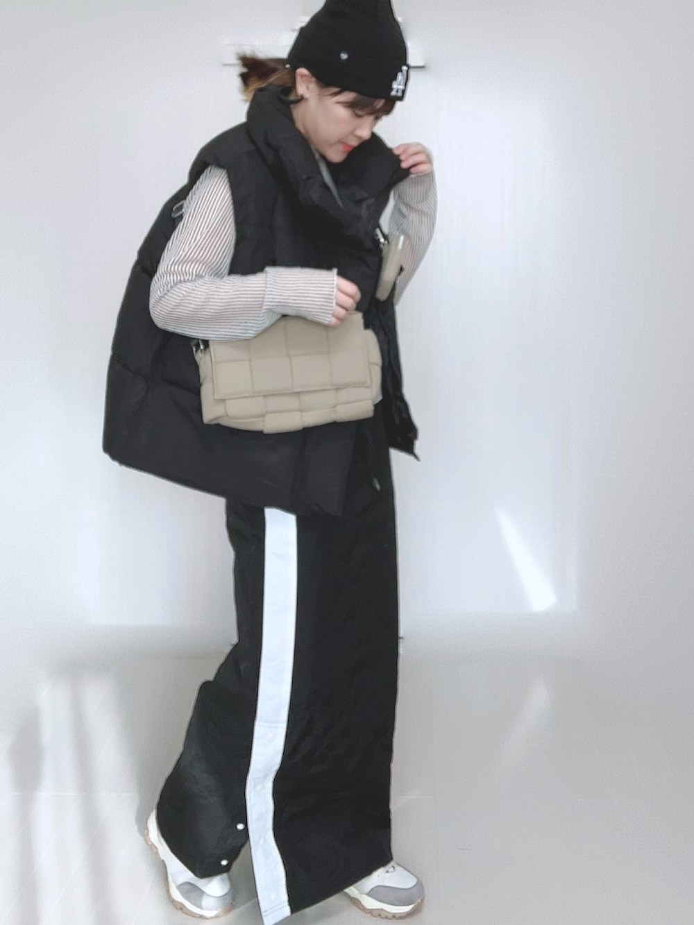 ブラック系のスカート、ブラック系のダウンベスト、ホワイト系のシャツ/ブラウスを着用したレディースの冬コーディネートの4枚目の写真