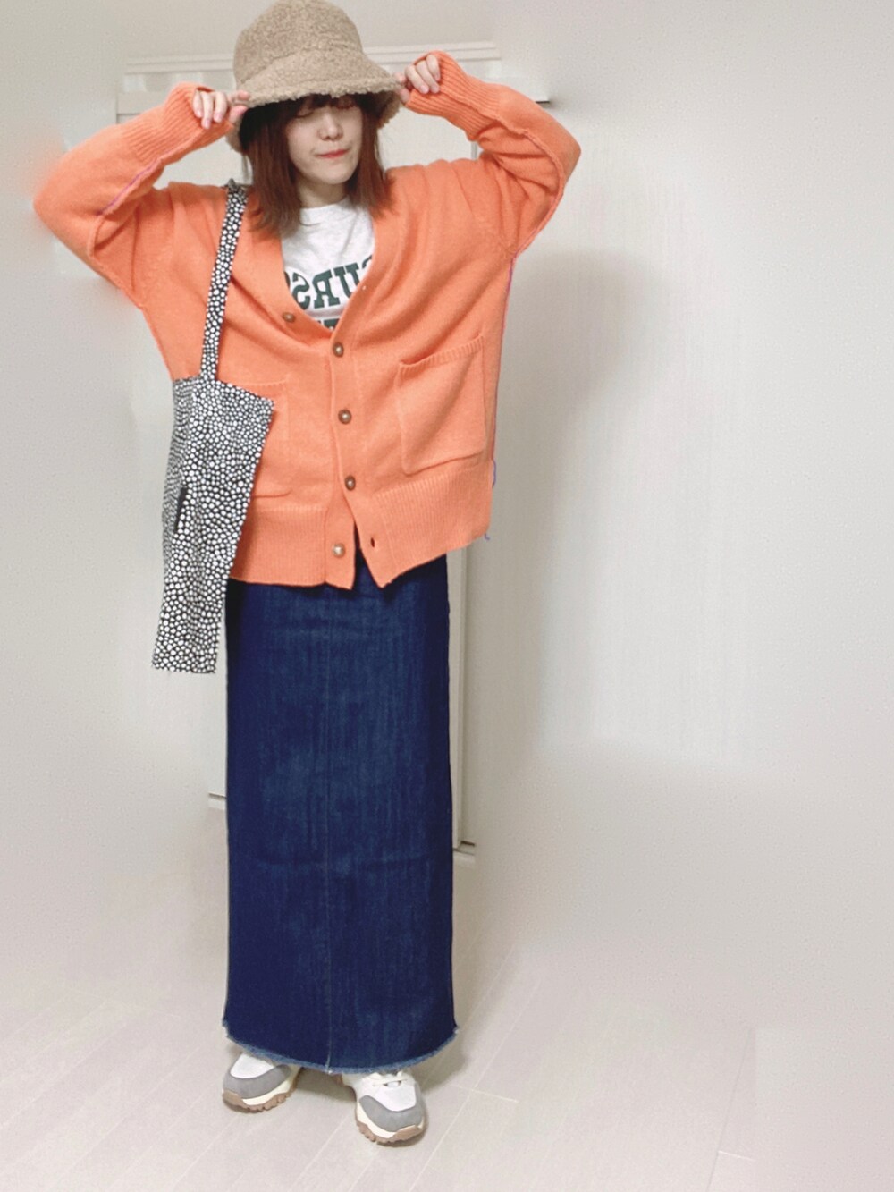 オレンジ系のカーディガン/ボレロ、ブルー系のデニムスカート、ベージュ系のスニーカーを着用したレディースの秋コーディネートの4枚目の写真