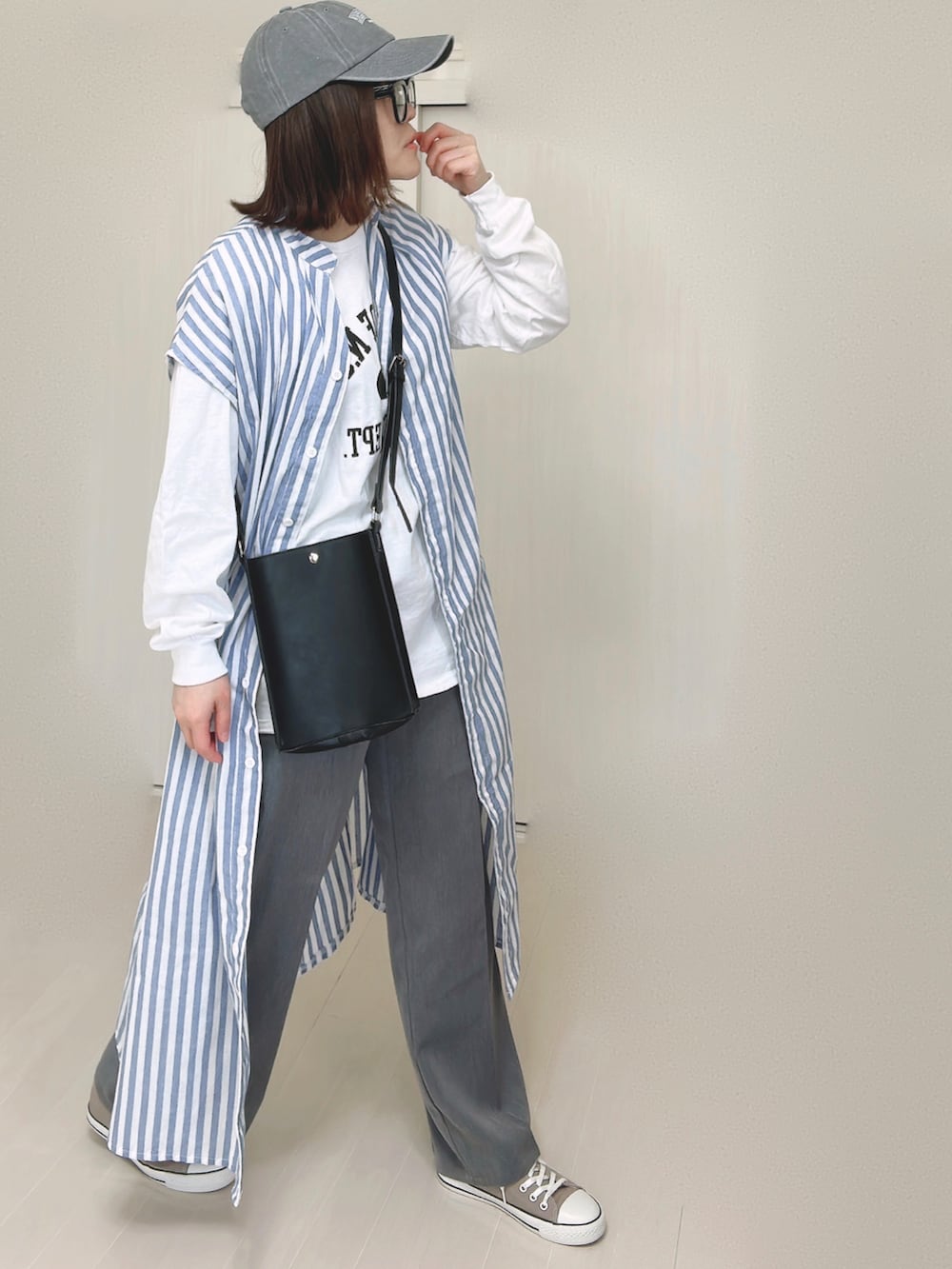 ブルー系のシャツワンピース、ホワイト系のTシャツ/カットソー、ブラック系のショルダーバッグを着用したレディースの春コーディネートの2枚目の写真