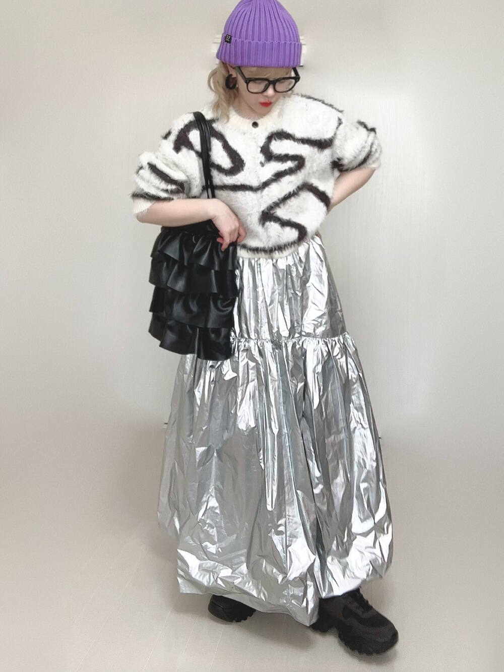 ホワイト系のカーディガン/ボレロ、シルバー系のスカート、ブラック系のスニーカーを着用したレディースの春コーディネートの2枚目の写真