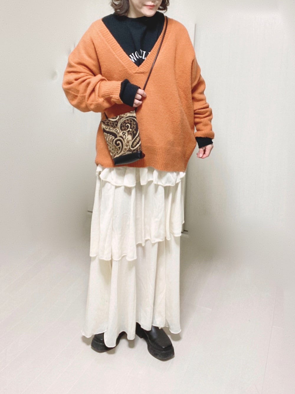 オレンジ系のニット/セーター、ブラック系のスウェット、ブラック系のショルダーバッグを着用したレディースの冬コーディネートの4枚目の写真