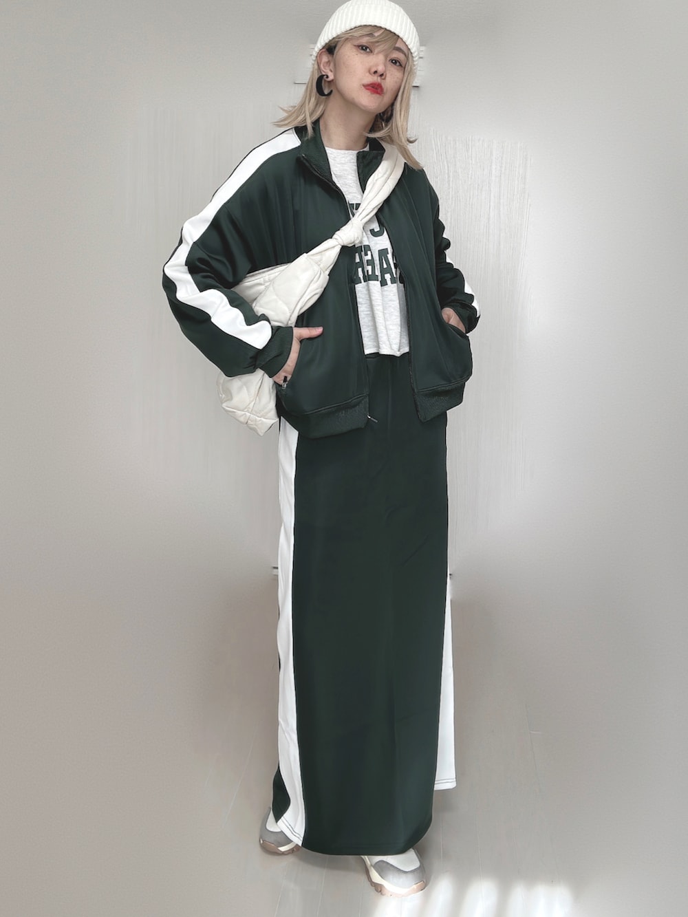 グリーン系のその他アウター、グリーン系のスカート、ホワイト系のショルダーバッグを着用したレディースの秋コーディネートの2枚目の写真